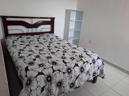 a bed with a black and white comforter on it at Jacaraipe, Serra ES in Serra