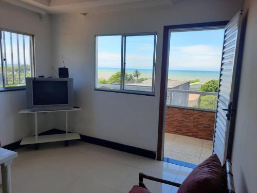 a living room with a tv and a view of the ocean at Jacaraipe, Serra ES in Serra