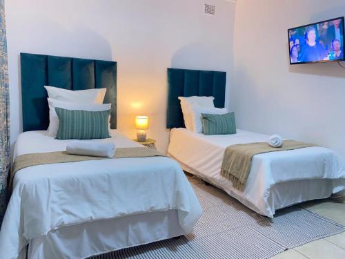 dwa łóżka siedzące obok siebie w pokoju w obiekcie Listos Guest House w mieście Empangeni