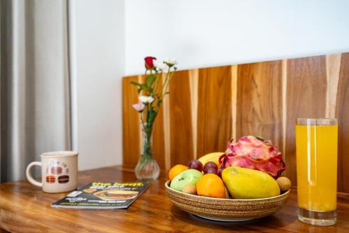 a bowl of fruit on a table with a glass of orange juice at Happiness Apartments Bali Ubud in Ubud