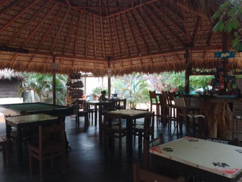 a restaurant with tables and chairs and a straw roof at Mondala Hostal Carrizalillo in Puerto Escondido