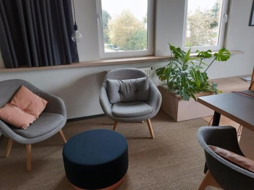 a living room with two chairs and a stool at Designhotel Whitman in Ascheberg
