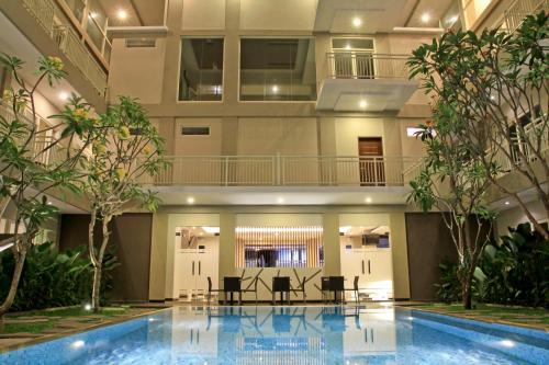 a hotel lobby with a pool and tables and trees at Choice Stay Hotel Denpasar in Denpasar
