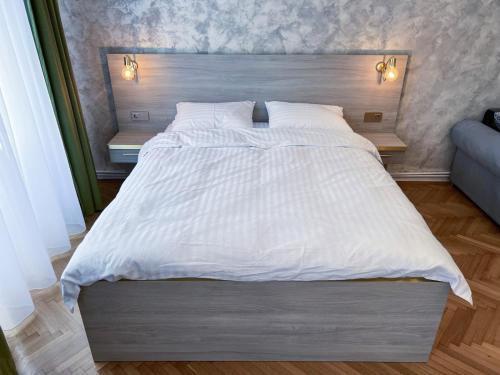 a bedroom with a large white bed with two lamps at Studio Excelsior 1 in Sibiu