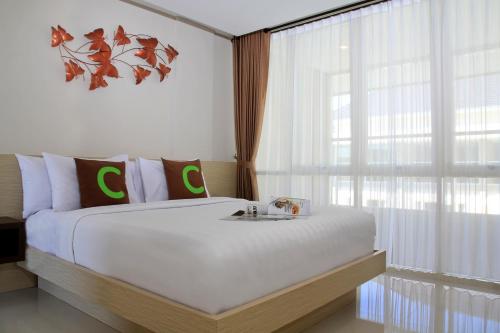 a bedroom with a large white bed and a window at Choice Stay Hotel Denpasar in Denpasar