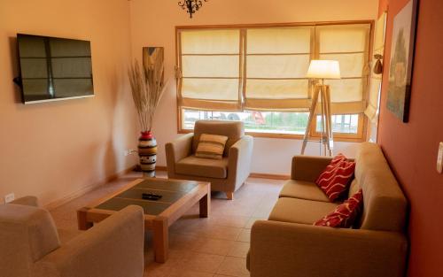 sala de estar con sofá, sillas y mesa en Casa en La Cascada en San Martín de los Andes