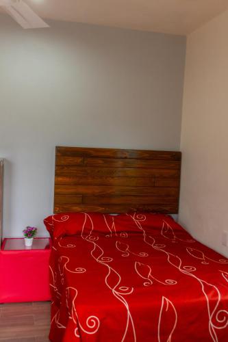 a red bed with a wooden headboard in a bedroom at Casa Biznaga in Oaxaca City