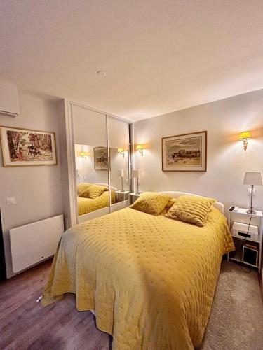 une chambre avec un grand lit avec une couverture jaune dans l'établissement L'idéal à Deauville, à Deauville