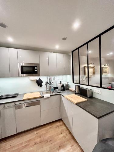 une cuisine avec des armoires blanches et des comptoirs noirs dans l'établissement L'idéal à Deauville, à Deauville