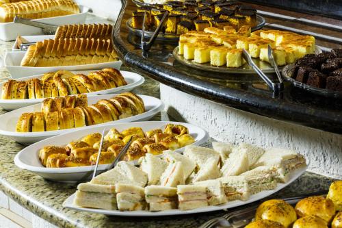 um buffet repleto de diferentes tipos de pastelarias e sobremesas em Hotel Damen em Foz do Iguaçu