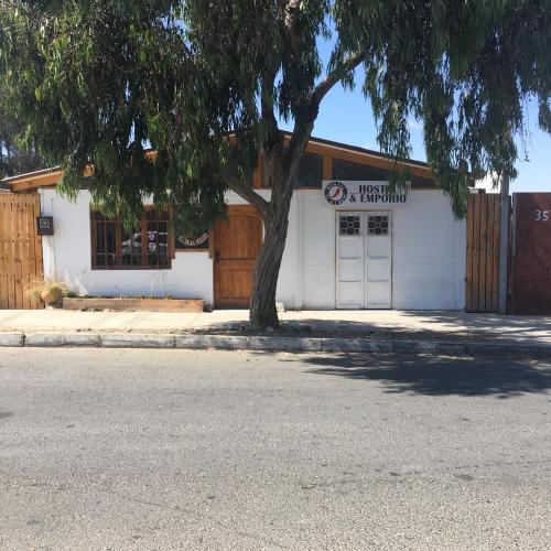 un edificio blanco con un árbol delante en Hostal El Aji Rojo, en Caldera