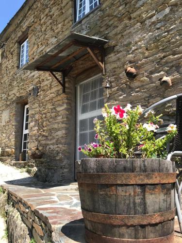 an old barrel with flowers in front of a stone building at Casa do Freire - Serra da Estrela in Aguincho
