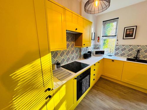 a yellow kitchen with yellow cabinets and a sink at Park Mount Residences - Luxury 3 Bedroom Flat In Leeds With Free Parking in Kirkstall