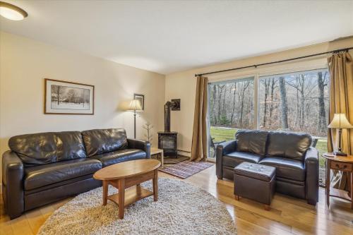 a living room with leather furniture and a large window at Cozy One-Bedroom Edgemont Condo with Ski Access & Fireplace B3 in Killington