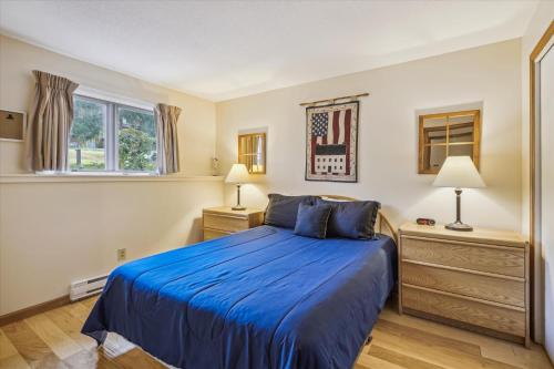 ein Schlafzimmer mit einem blauen Bett und zwei Nachttischen in der Unterkunft Cozy one bedroom Edgemont B3 condo ski back trail in Killington