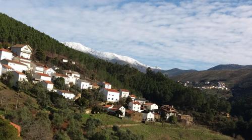 a village on a hill with a snow covered mountain at Casa do Freire - Serra da Estrela in Aguincho