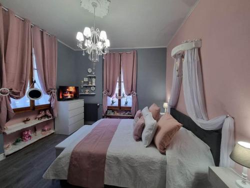 - une chambre dotée d'un lit avec des rideaux roses et un lustre dans l'établissement La chatellenie Gîte de caractère de 1638., à Évaux-les-Bains