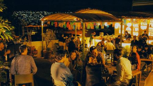 un grupo de personas sentadas en un bar por la noche en Viajero Oaxaca Hostel, en Oaxaca City