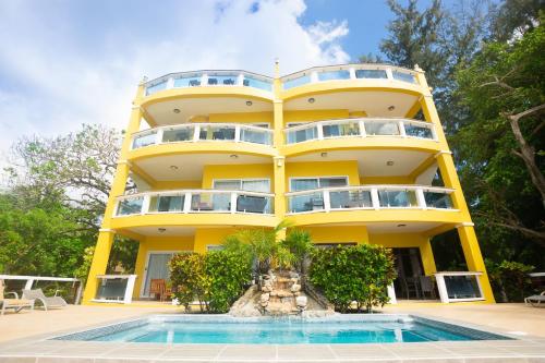 un edificio amarillo con una piscina frente a él en Del Playa Penthouse #6 Condo, en West End