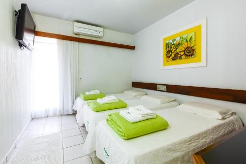 Habitación con 3 camas y toallas verdes. en Hotel Damen, en Foz do Iguaçu