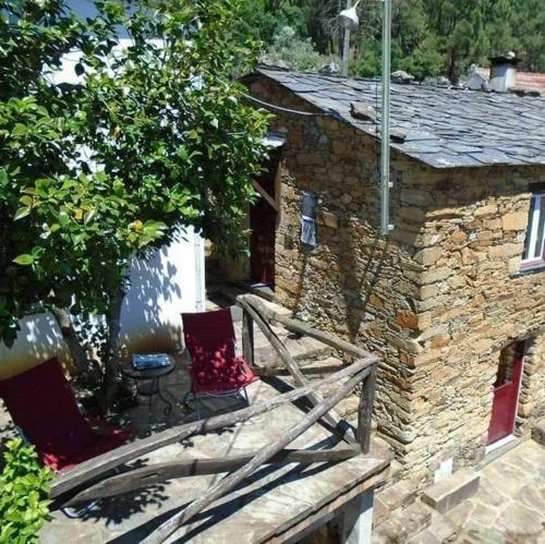 a stone house with two chairs on a porch at Casa do Galvão -Turismo Rural - Serra da Estrela in Aguincho