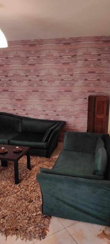 a living room with two green couches and a brick wall at La Casa in Mesinón
