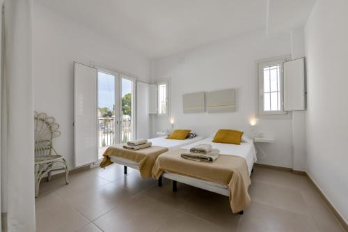 Un dormitorio blanco con 2 camas y una silla en EL PASEO - By Almarina Villas, en Teulada