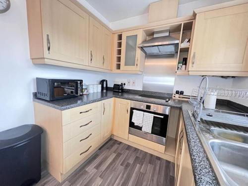 een keuken met houten kasten en een fornuis met oven bij Ava's Apartment - 1 Bedroom In Solihull Centre - Free Parking - Wi-Fi in Solihull