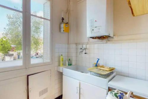 une cuisine blanche avec un évier et une fenêtre dans l'établissement Appartment Close to Monuments, à Paris