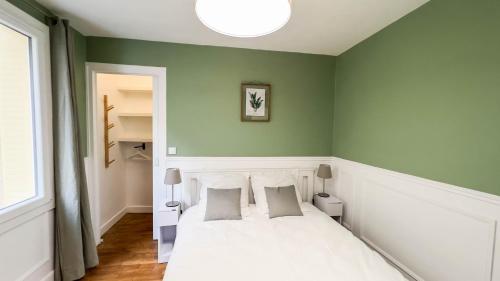 une chambre avec un lit blanc et des murs verts dans l'établissement Appartement 4 étoiles en centre ville de Vichy - Le Basile, à Vichy
