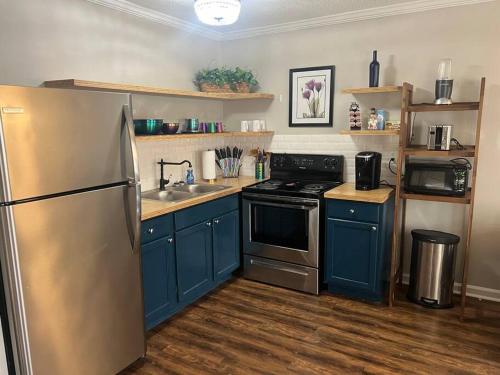 a kitchen with blue cabinets and a stainless steel refrigerator at Indigo DowntownWalkable KingBed in Raleigh