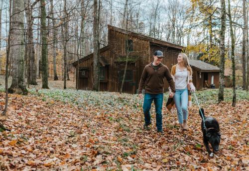 a man and woman walking a dog in the woods at Finnwood - A Pet Friendly Woodland Retreat in Suttons Bay
