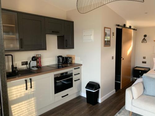 una cocina con armarios negros y un sofá en una habitación en Angusfield Cabins, en Sconser
