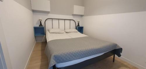 uma cama num quarto branco com duas mesas azuis em FIRST -- Green Żoliborz apartment 1 em Varósvia