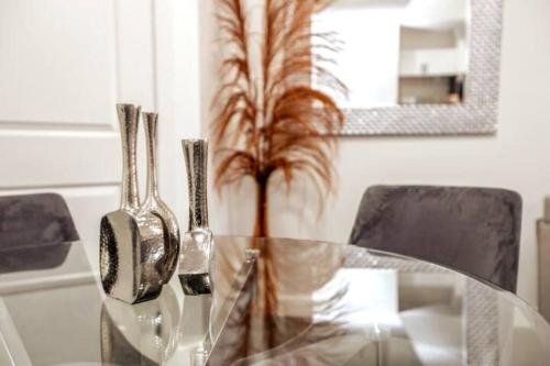 una mesa de cristal con dos utensilios de plata y una planta en Chic Suite - Long Stays - King Bed - Fireplace & WiFi, en Edmonton
