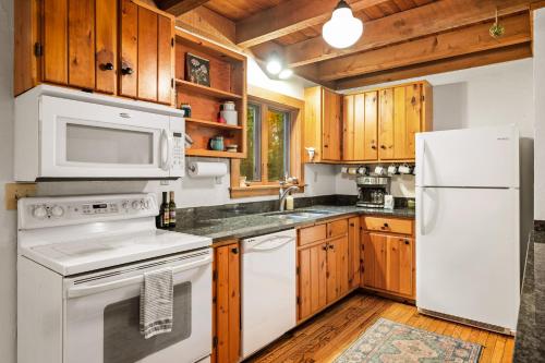 a kitchen with white appliances and wooden cabinets at Finnwood - A Pet Friendly Woodland Retreat in Suttons Bay