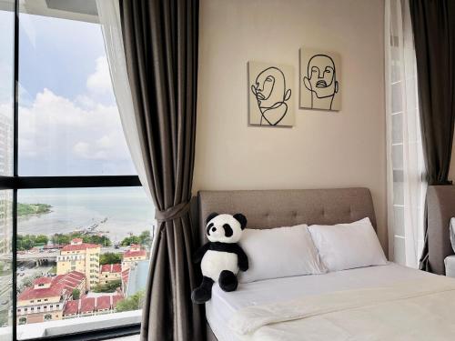 a panda bear sitting on a bed in front of a window at New 2BR or 3BR Cozy Urban Suite Homestay at Georgetown8-10pax by URBAN STAYCATIONS LOD in Jelutong