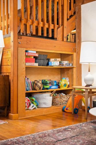 a book shelf with toys and a table and a lamp at Finnwood - A Pet Friendly Woodland Retreat in Suttons Bay
