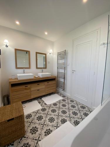 une salle de bain avec deux lavabos et deux miroirs dans l'établissement Magnifique maison-Vue mer exceptionnelle., à Audierne