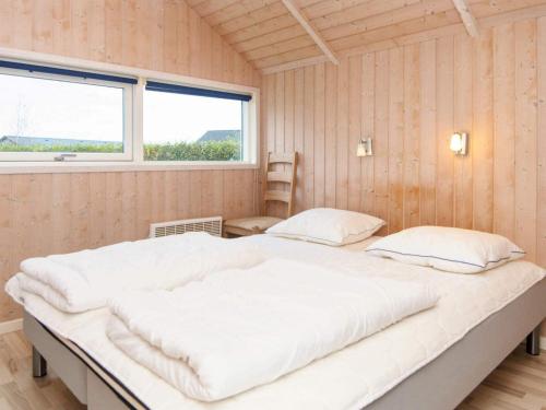 a large bed in a room with two windows at 4 star holiday home in Sydals-By Traum in Neder Lysabild