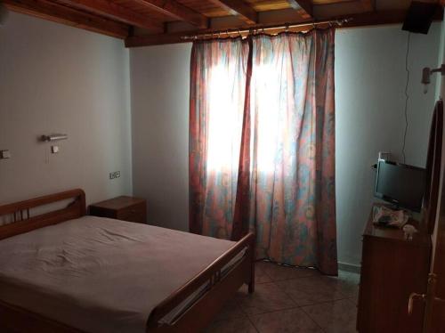 a bedroom with a bed and a window with a curtain at A CASA D'IRENE in Votsalákia