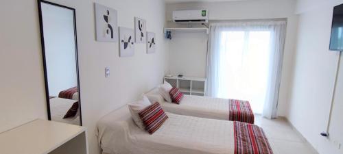 Habitación blanca con 2 camas y espejo. en Departamento Italia 798 en San Miguel de Tucumán