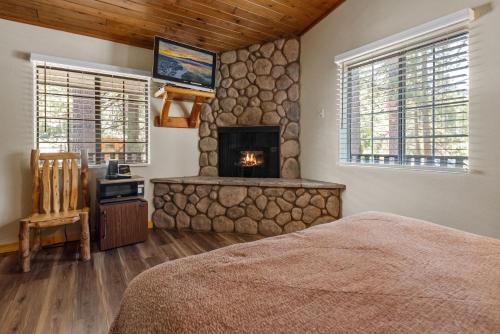 a bedroom with a stone fireplace and a bed at Black Forest Lodge in Big Bear Lake