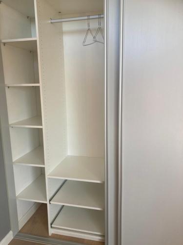 a closet with white shelves and a refrigerator at Værelse, bad og toilet i villa in Næstved