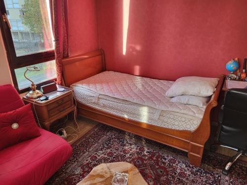 een kleine slaapkamer met een bed en een rode muur bij Studio de Luxe in Vitry-le-François