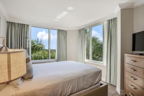 a bedroom with a bed and a television and windows at Marco Beach Ocean Resort 714 in Marco Island