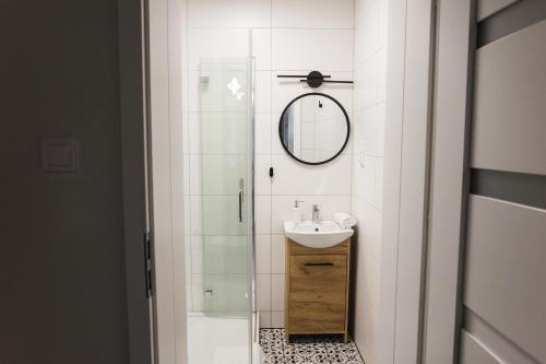 een witte badkamer met een wastafel en een spiegel bij CracWoW K8 No.10 Apartment in Krakau