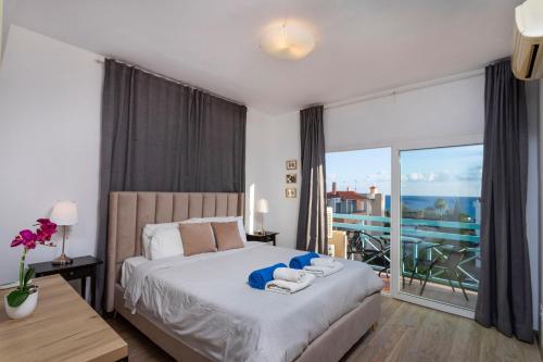 a bedroom with a large bed and a balcony at Palm Beach Apartment by TrulyCyprus in Limassol