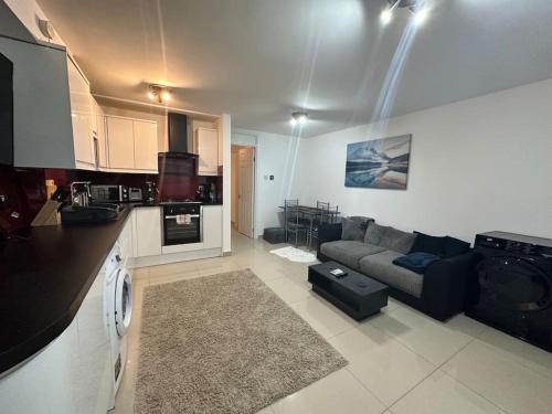 a large living room with a couch and a kitchen at Lovely 1 bedroom flat in Chigwell
