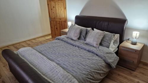 um quarto com uma cama grande com lençóis e almofadas roxos em Comfortable 2 bedroom house with free parking and great transport links em Dagenham